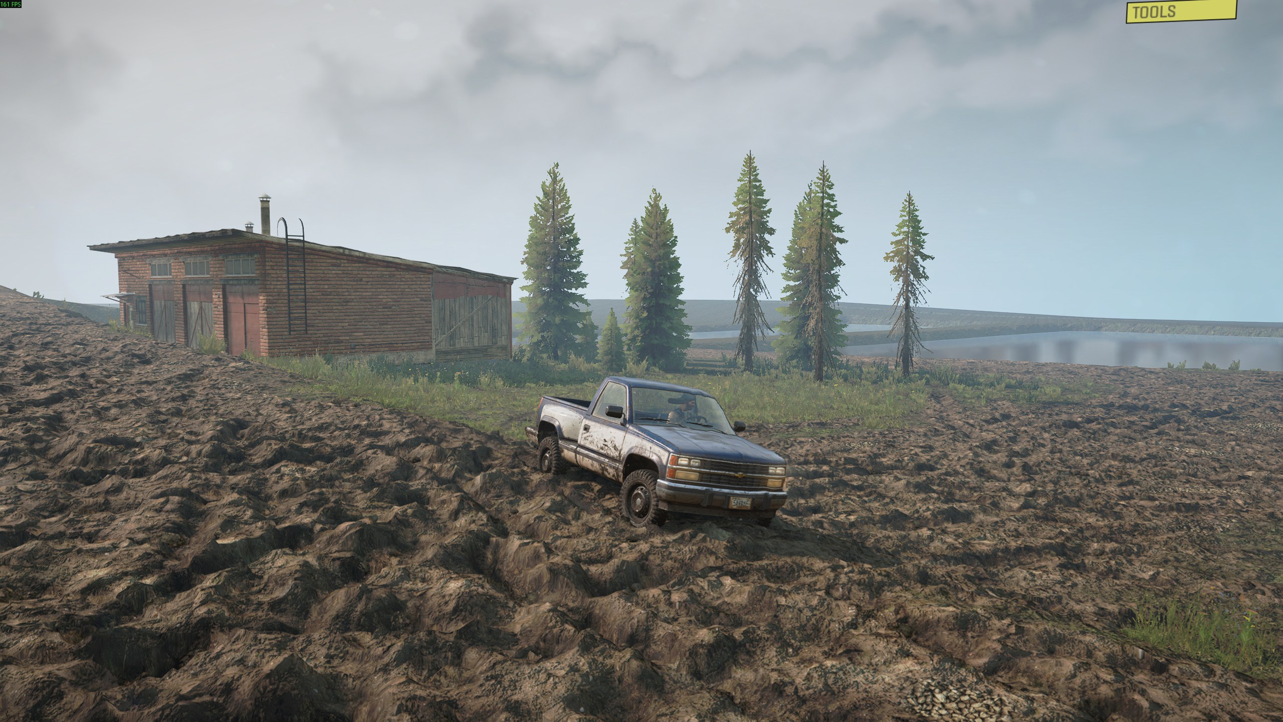 A pickup truck driving through generated mud beside a building, trees, and water on a playable MapToPlay export in SnowRunner.